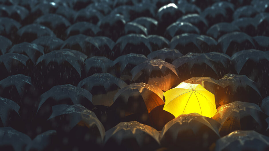 a single glowing umbrella in a crowd of dark umbrellas